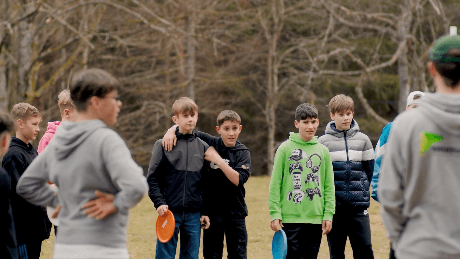 Eine Schulklasse mit Frisbees auf der Wiese vor dem Gruppenhaus